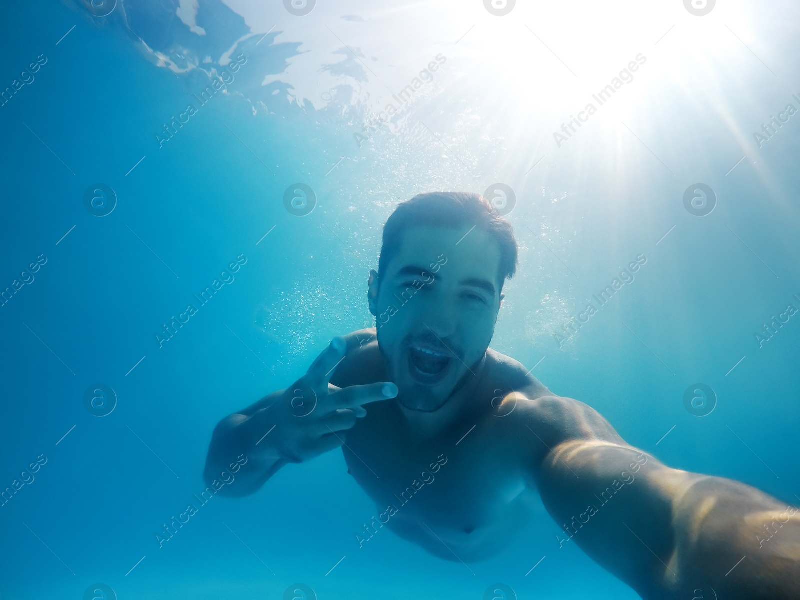 Photo of Handsome young man swimming in pool, underwater view