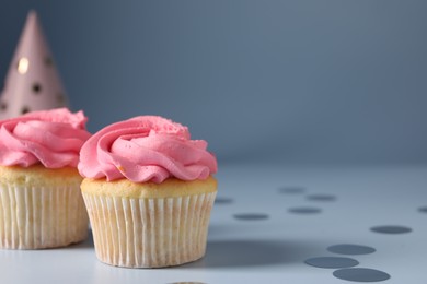 Delicious cupcakes with bright cream and confetti on light background, space for text