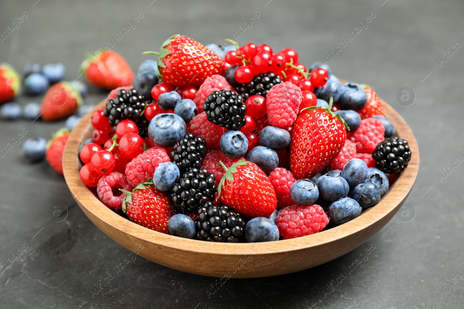 Photo of Mix of different fresh berries in bowl on grey table