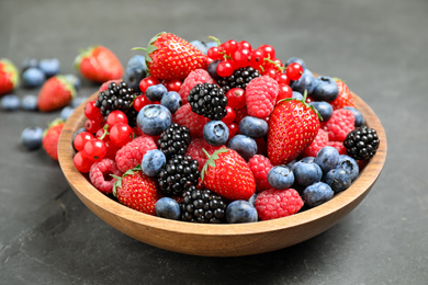 Photo of Mix of different fresh berries in bowl on grey table