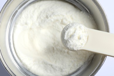 Scoop of powdered infant formula over can, top view. Baby milk