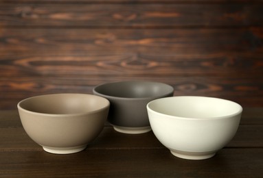 Photo of Stylish empty ceramic bowls on wooden table. Cooking utensils