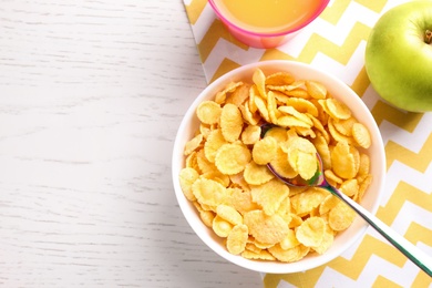 Flat lay composition with cornflakes on white wooden table, space for text. Healthy breakfast