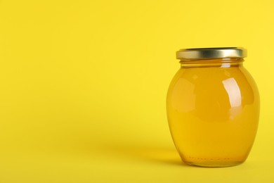 Jar of organic honey on yellow background. Space for text