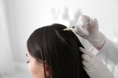 Photo of Young woman with hair loss problem receiving injection in salon, closeup