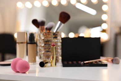 Photo of Sponge and other beauty products on white table in makeup room, selective focus