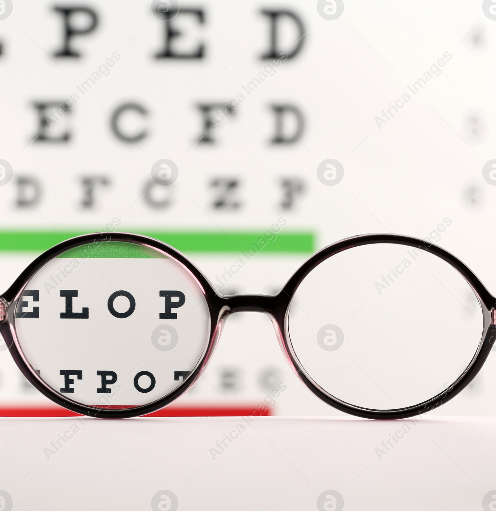 Glasses on table against eye chart, view through lenses Photo of Glasses on table against eye chart, view through lenses