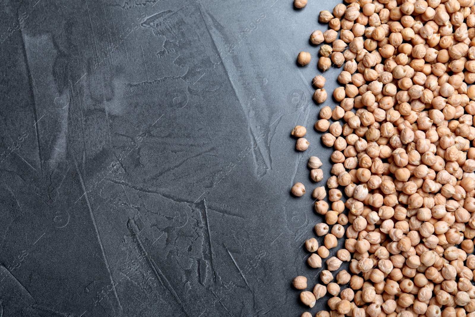 Photo of Raw chickpeas on grey table, top view. Space for text