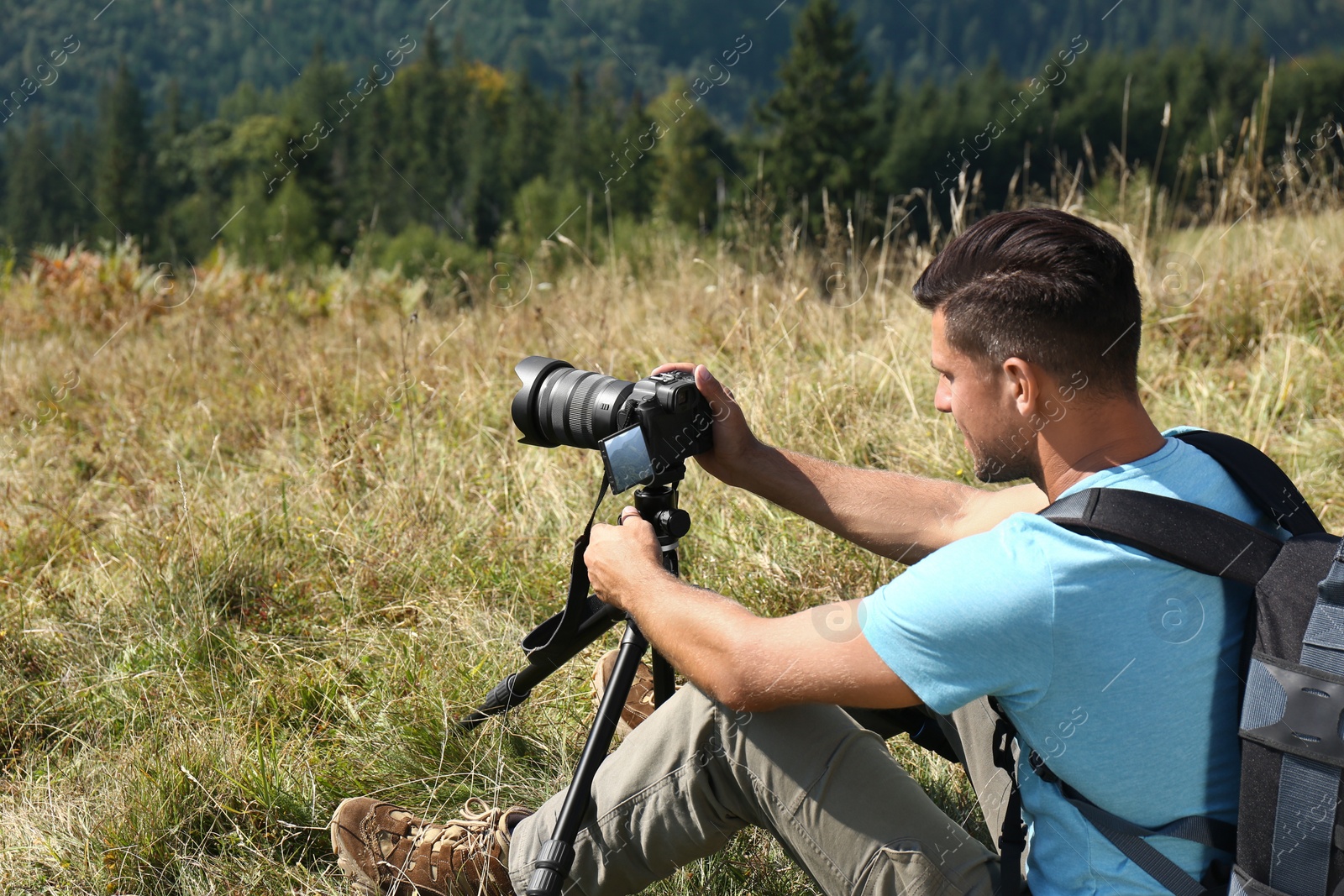 Photo of Man taking photo of nature with modern camera on tripod outdoors