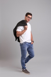 Photo of Handsome young man in casual clothes with black jacket and glasses on grey background