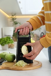 Photo of Woman grating fresh green apple at kitchen counter, closeup