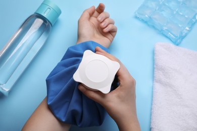 Photo of Woman with cold compress on light blue background, top view. Heat stroke treatment