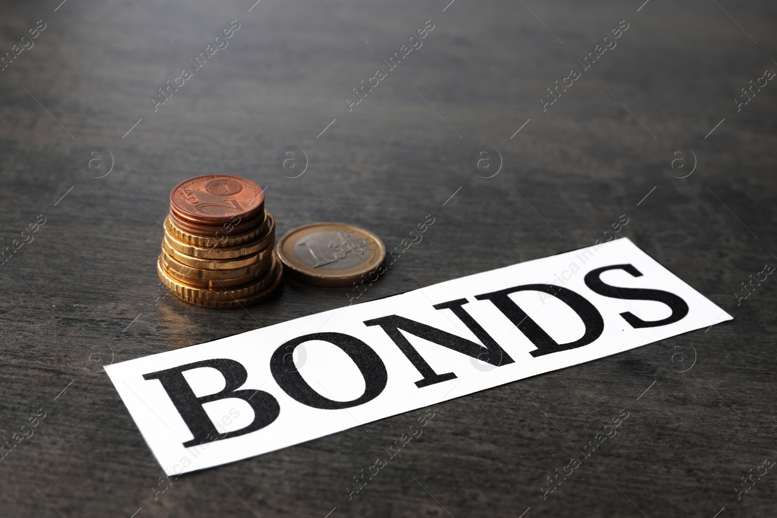 Photo of Paper with word Bonds and stacked coins on grey table