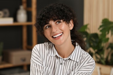 Photo of Portrait of beautiful woman with curly hair indoors. Attractive lady smiling and posing for camera