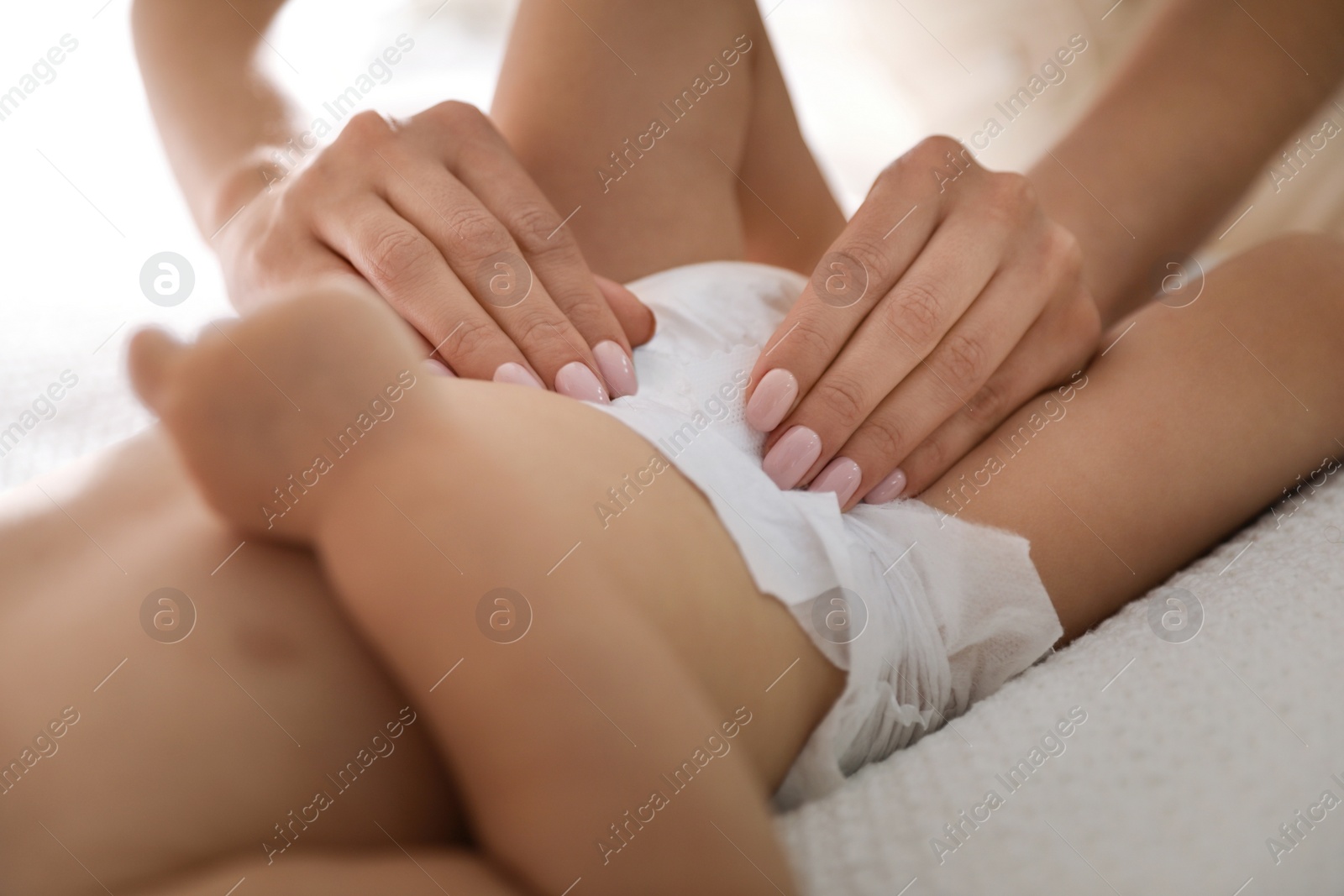 Photo of Mother changing baby's diaper on bed at home, closeup