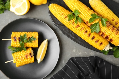 Photo of Flat lay composition of grilled corn cobs on grey table