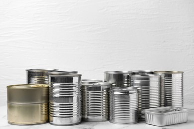 Photo of Many closed tin cans on white marble table