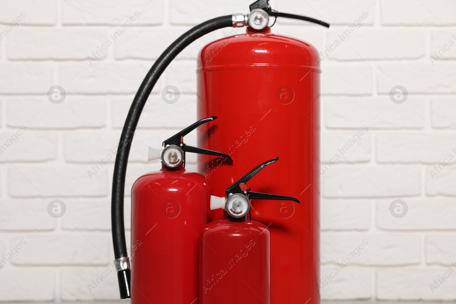 Photo of Red fire extinguishers near white brick wall