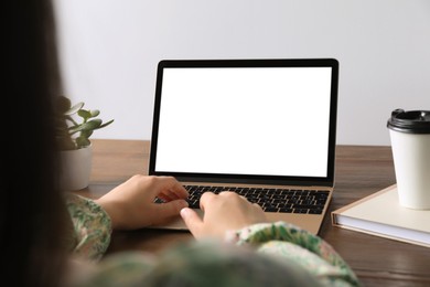 Woman working on laptop at wooden table, closeup. Mockup for design