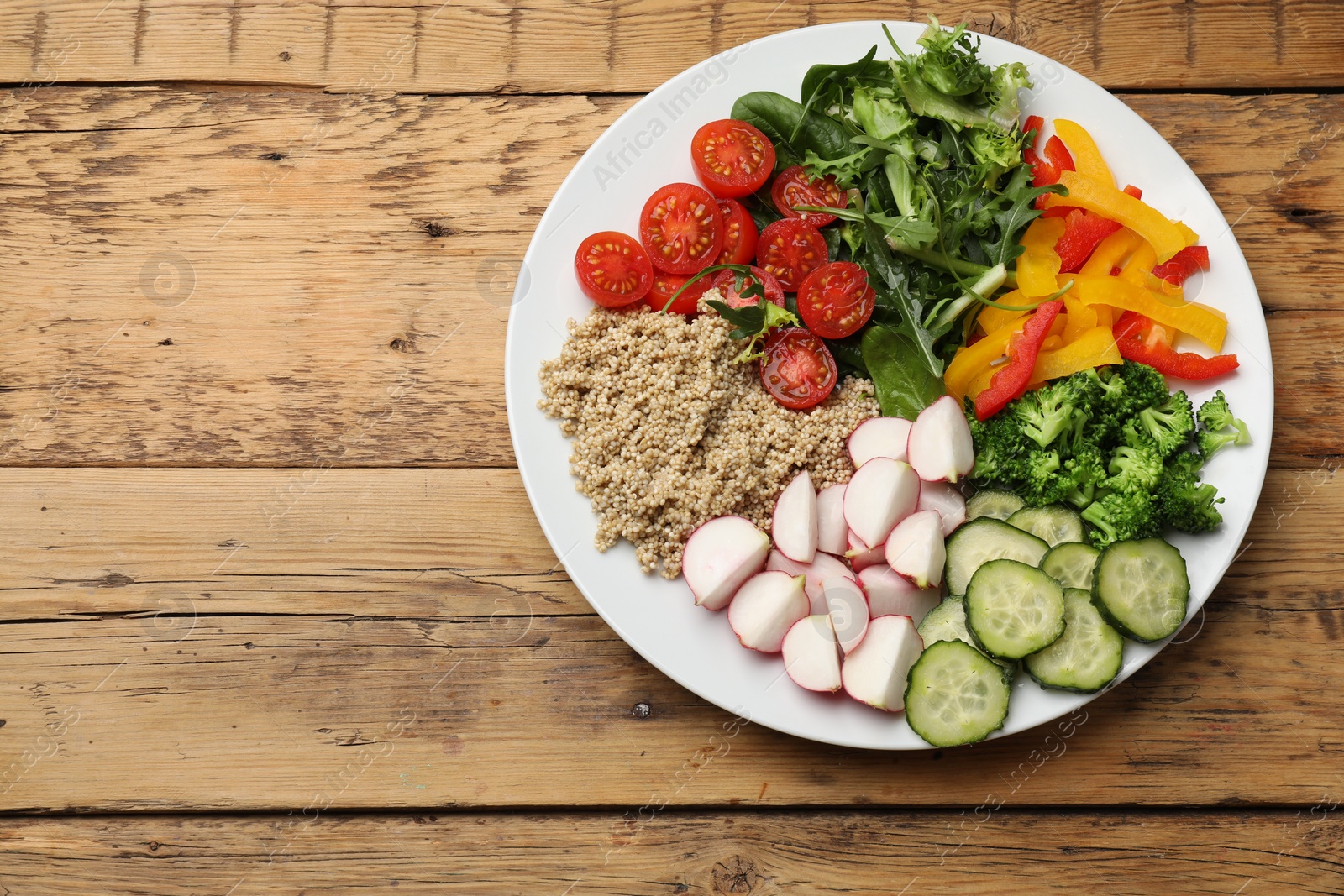 Photo of Vegetarian diet. Plate with tasty vegetables and quinoa on wooden table, top view. Space for text