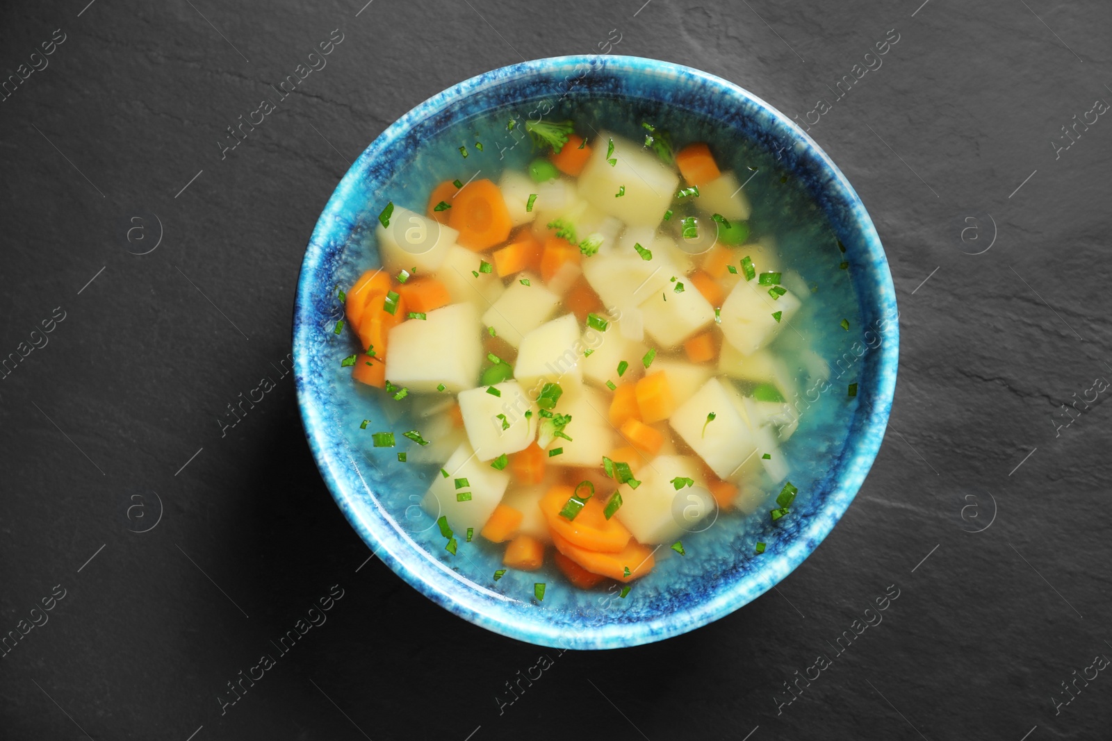 Photo of Bowl of fresh homemade vegetable soup on black background, top view