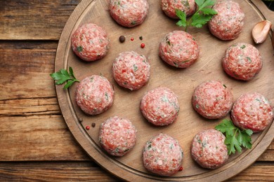 Photo of Many fresh raw meatballs and ingredients on wooden table, top view