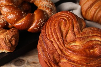 Photo of Different tasty freshly baked pastries on wooden table, closeup