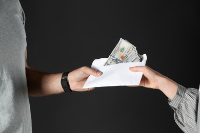 Photo of Woman giving bribe money to man on black background, closeup