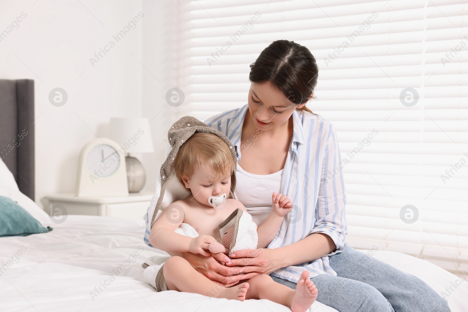 Photo of Mother wrapping her cute little baby with towel after bathing on bed
