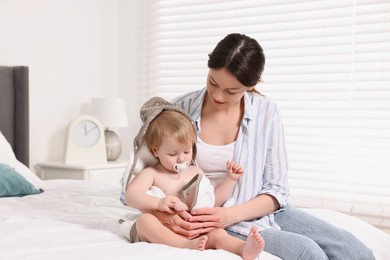 Photo of Mother wrapping her cute little baby with towel after bathing on bed