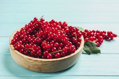 Photo of Delicious red currants on light blue wooden table