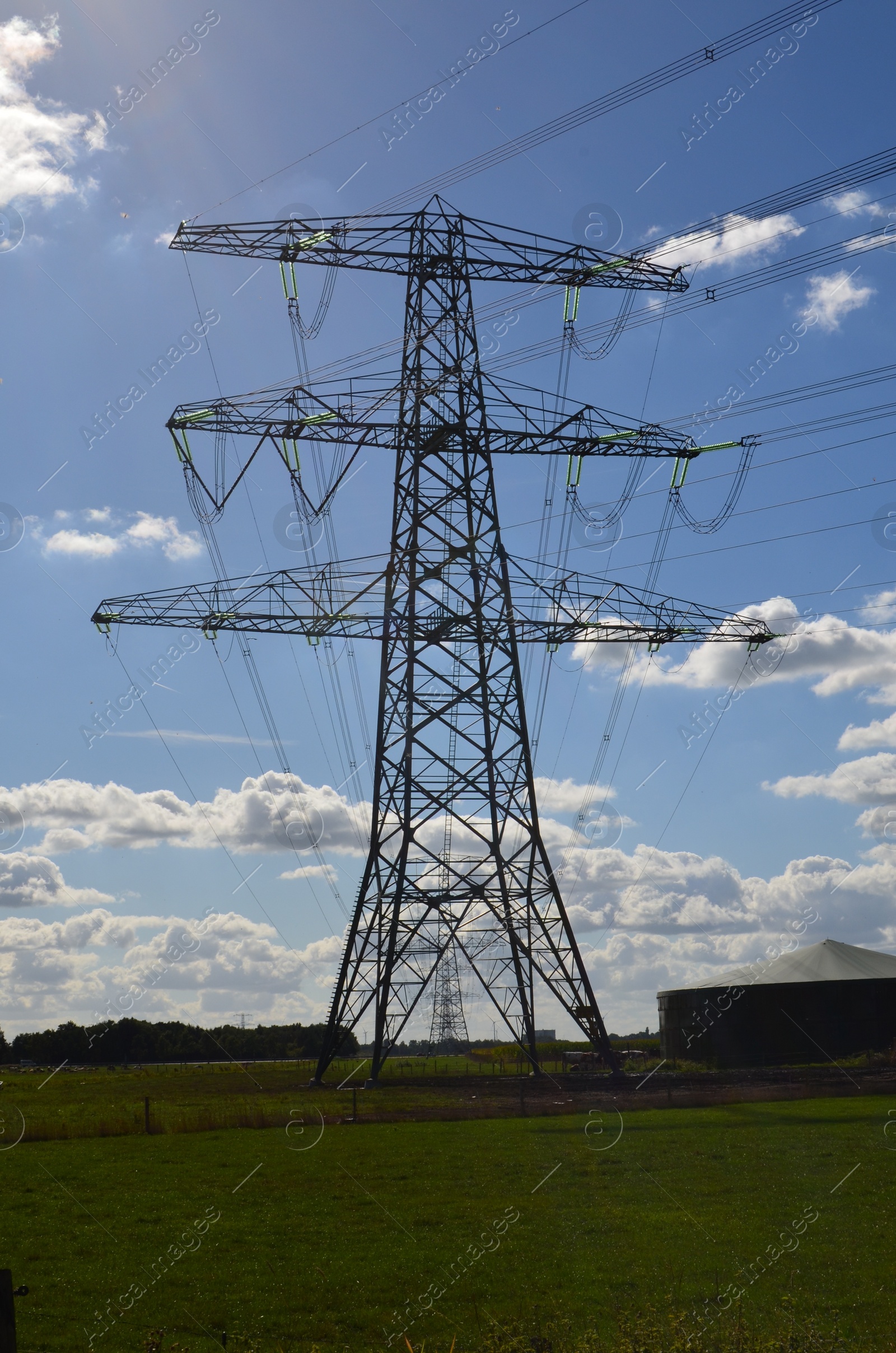 Photo of High voltage tower with electricity transmission power lines in field on sunny day