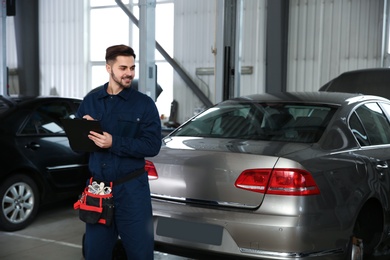 Portrait of technician with clipboard at automobile repair shop