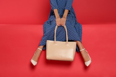 Woman with stylish bag on red background, closeup