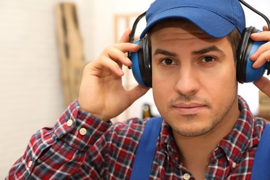 Worker wearing safety headphones indoors. Hearing protection device