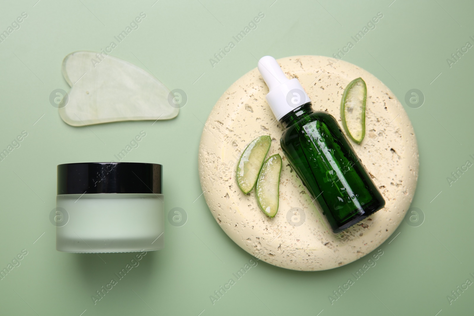 Photo of Flat lay composition with cosmetic products and cut aloe leaves on pale green background