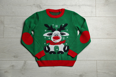 Warm Christmas sweater on wooden table, top view