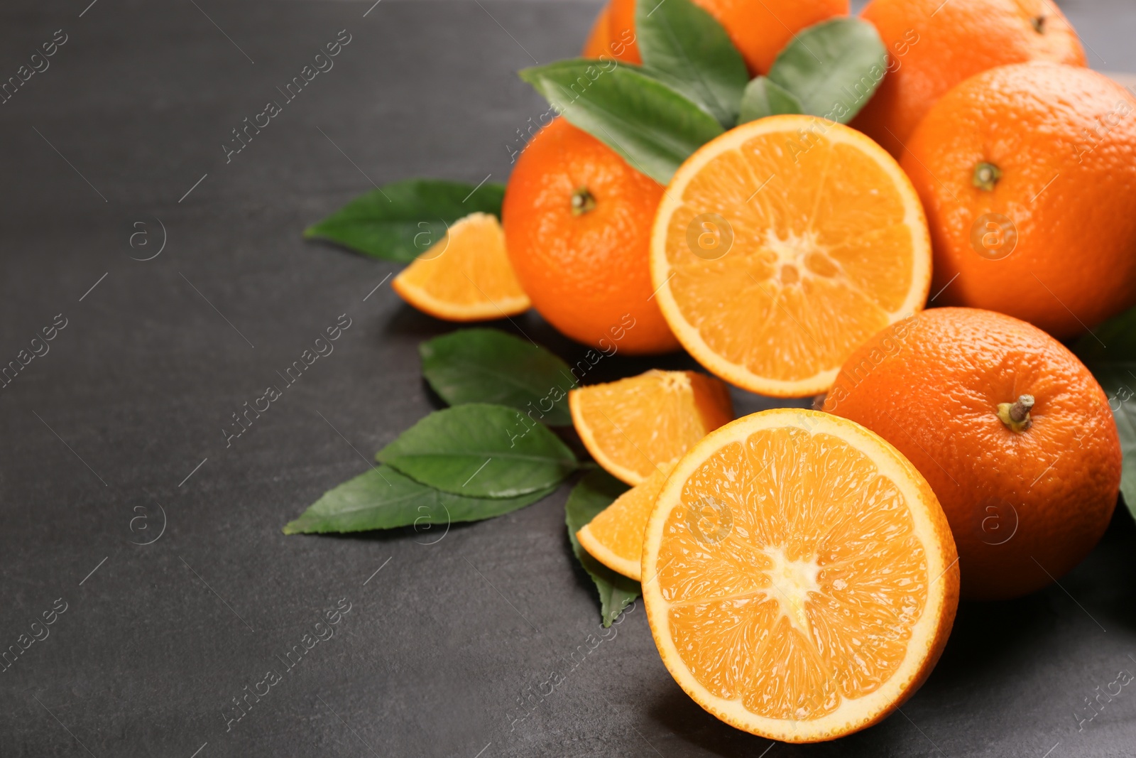 Photo of Delicious ripe oranges on black table. Space for text