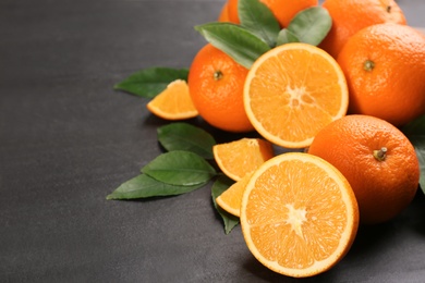 Photo of Delicious ripe oranges on black table. Space for text