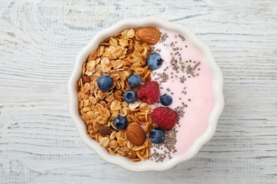 Photo of Tasty homemade granola served on white wooden table, top view. Healthy breakfast