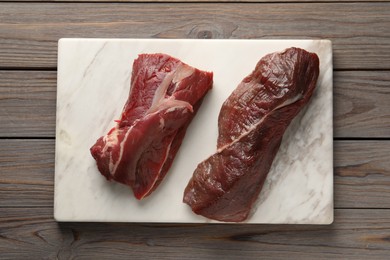 Pieces of raw beef meat on wooden table, top view
