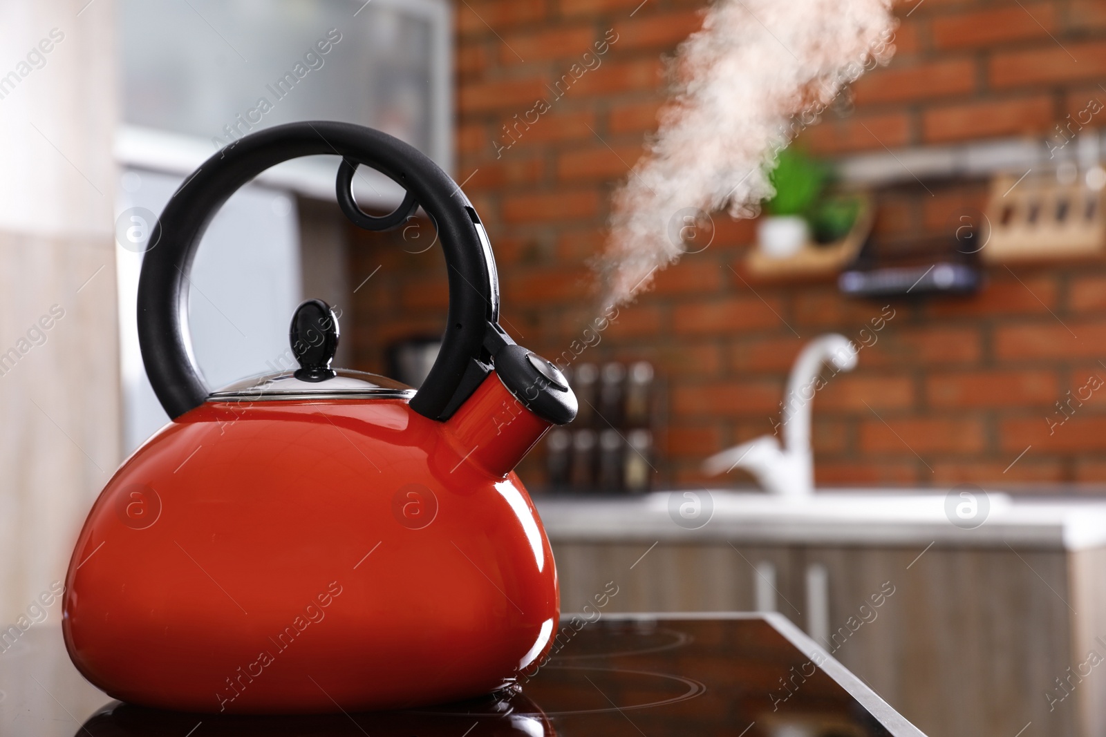 Photo of Modern kettle with whistle on stove in kitchen, space for text