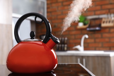 Modern kettle with whistle on stove in kitchen, space for text