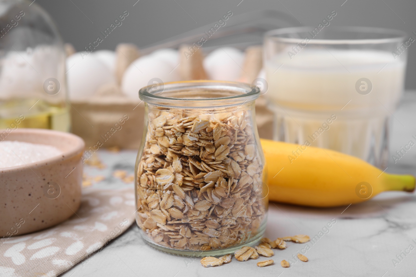 Photo of Different ingredients for cooking tasty oatmeal pancakes on white marble table