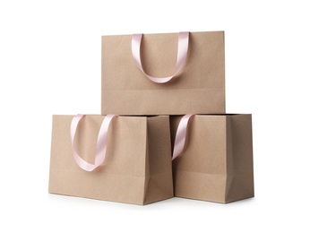 Photo of Paper shopping bags with ribbon handles on white background. Mockup for design