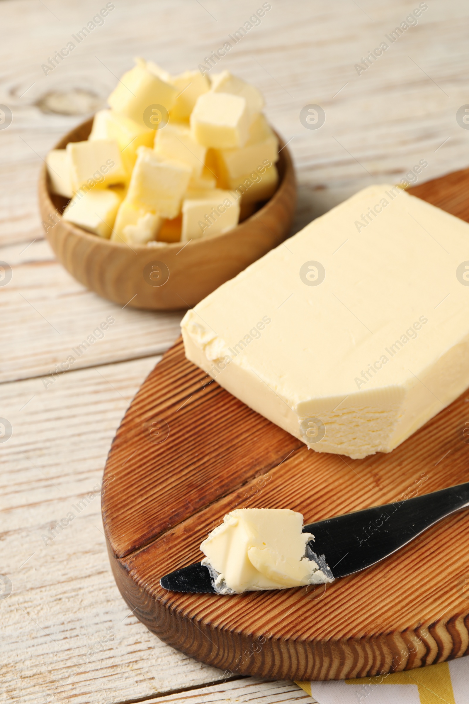 Photo of Tasty butter and knife on light wooden table, closeup