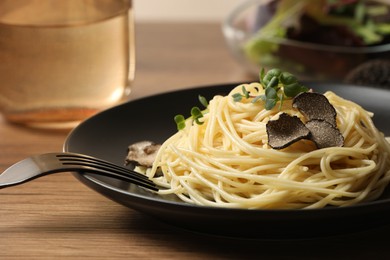 Photo of Tasty spaghetti with truffle on wooden table, closeup