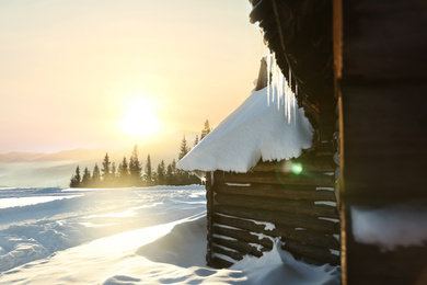 Photo of Wooden house with icicles on snowy day. Winter vacation