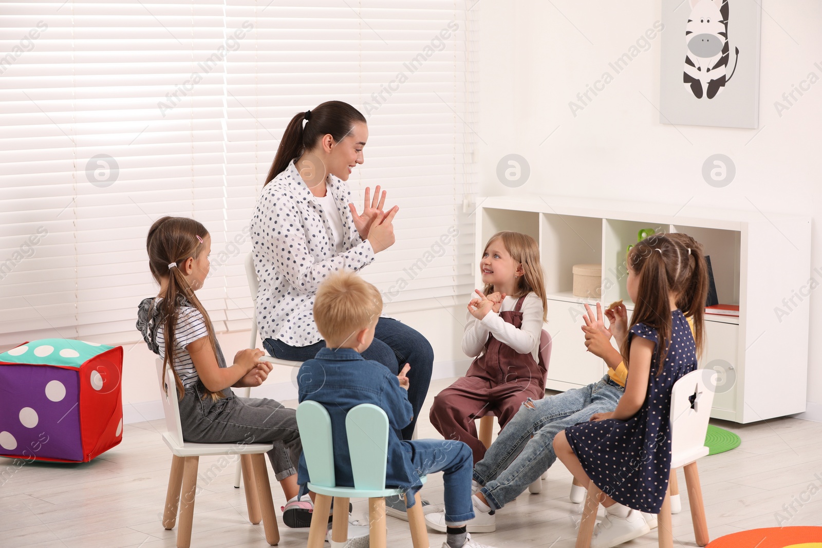 Photo of Nursery teacher and group of cute little children learning numbers in kindergarten. Playtime activities