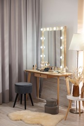 Makeup room. Stylish mirror with light bulbs on dressing table and chair indoors